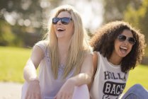 Two young female friends laughing in park — Stock Photo