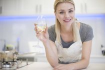 Портрет молодой женщины, пьющей бокал белого вина на кухне — стоковое фото