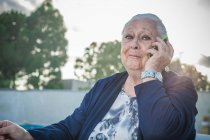 Donna anziana utilizzando smartphone in cortile — Foto stock