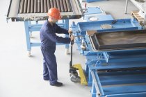 Worker using manual pallet jack in industrial plant — Stock Photo