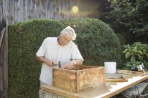 Senior man making wooden crate in garden — Stock Photo