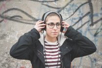 Adolescente con auriculares por pared de graffiti - foto de stock