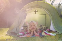Ritratto di ragazza sdraiata a guardare dalla tenda da giardino — Foto stock