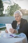 Старшая женщина использует цифровой планшет на заднем дворе — стоковое фото