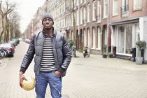 Portrait d'un jeune homme tenant un ballon de football dans la rue, Amsterdam, Pays-Bas — Photo de stock