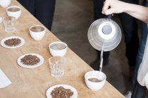 Immagine ritagliata del venditore di caffè versando acqua calda nella tazza di caffè — Foto stock
