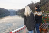 Coppia eterosessuale in piedi accanto al lago, Lombardia, Italia, vista posteriore — Foto stock