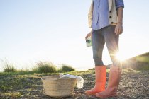 Young woman in wellies standing against sunset — Stock Photo