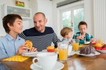 Чоловік середнього віку та сім'я мають чай за кухонним столом — стокове фото