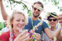 Adult friends wrapping each other in streamers at sunset party in park — Stock Photo