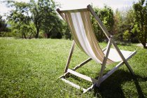 Cadeira de praia vazia na grama iluminada sol — Fotografia de Stock