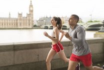 Male and female runners running along Southbank, London, UK — Stock Photo