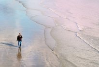 High angle front view of mature man walking on beach along coastline — Stock Photo