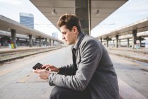 Retrato de jovem empresário viajante usando tablet digital na estação de trem . — Fotografia de Stock