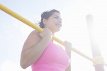 Jeune femme faisant des hauts de menton sur barre d'exercice — Photo de stock