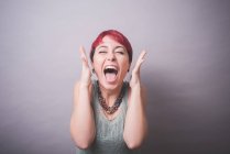Студійний портрет молодої жінки з коротким рожевим волоссям, що сміється — стокове фото