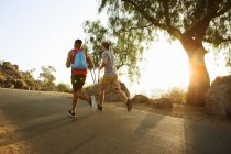 Two male friends running, outdoors, rear view — Stock Photo