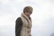 Hombre adulto medio con chaleco peludo y sombrero de trampero - foto de stock