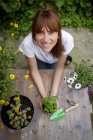 Visão de ângulo alto da mulher adulta média segurando planta de manjericão, sorrindo para a câmera — Fotografia de Stock