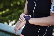 Cropped shot of young female runner setting smartwatch — Stock Photo