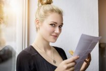 Junge Frau liest Papierkram auf Fensterbank — Stockfoto