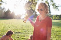 Молода жінка п'є вино на вечірці парку заходу сонця — стокове фото