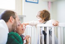 Mid adult couple laughing with toddler daughter in crib — Stock Photo