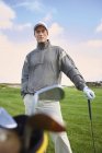 Golfer hält Goldschläger in der Tasche, blickt in die Kamera — Stockfoto