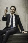 Reifer Geschäftsmann, schaut aufs Smartphone, lächelt — Stockfoto