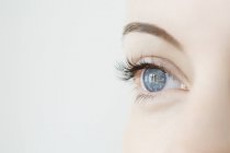 Studio close-up shot of mid adult woman gazing blue eye — Stock Photo
