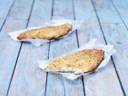 Due pezzi di pesce platano impanati fritti sul tavolo di legno — Foto stock