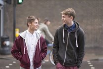 Due amici maschi attraversano la strada in città — Foto stock