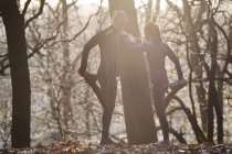 Paar im Wald lehnt sich mit erhobenem Bein aneinander — Stockfoto