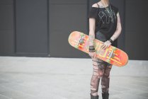Cropped shot of young female punk holding skateboard — Stock Photo