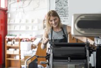 Jovem mulher trabalhando na tradicional máquina de impressão de tipografia em oficina — Fotografia de Stock