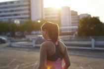 Young female runner on sunlit rooftop — Stock Photo