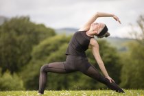Reife Frau praktiziert Yoga-Pose im Feld — Stockfoto
