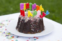 Birthday cake with candles on garden table — Stock Photo
