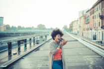 Молодая женщина поет под музыку со смартфона в городе — стоковое фото
