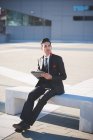 Молодой бизнесмен, использующий цифровой планшет на скамейке — стоковое фото