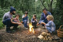 Due padri e quattro ragazzi brindano ai marshmallow sul falò nella foresta — Foto stock