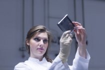 Young female scientist examining microscopy slide in lab — Stock Photo