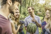 Männliche und weibliche Freunde im Garten mit Wassermelone — Stockfoto