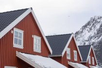 Три дома и заснеженная гора, Свольваер, Лофские острова, Норвегия — стоковое фото