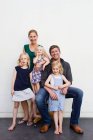 Ritratto di famiglia di genitori e tre giovani figlie davanti al muro bianco — Foto stock