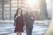 Couple walking across rooftop parking lot in city — Stock Photo