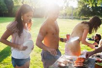 Group of friends barbecuing at sunset park party — Stock Photo
