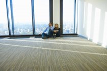 Empresária e homem sentado em frente à janela no escritório do arranha-céu vazio, Bruxelas, Bélgica — Fotografia de Stock