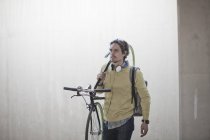 Hombre adulto medio llevando bicicleta por el paso subterráneo de la ciudad - foto de stock