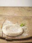 Circle of prepared pizza dough on chopping board sprinkled with flour — Stock Photo